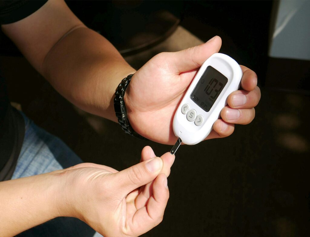 Close-up of hands using a glucometer to check blood sugar levels for diabetes management.