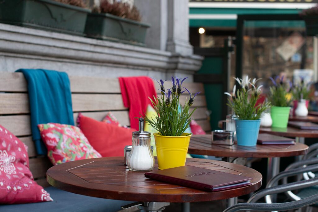 Cozy outdoor restaurant seating featuring colorful plants and cushions for a relaxing atmosphere.