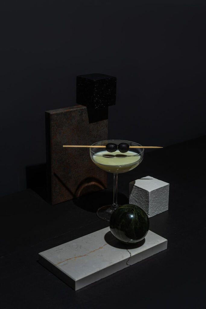 A modern minimalist composition featuring geometric shapes and a cocktail glass with olives.