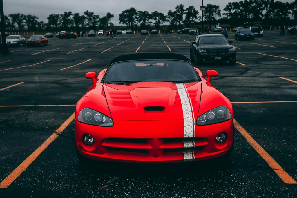 Vibrant red sports car parked in an empty lot with overcast skies.